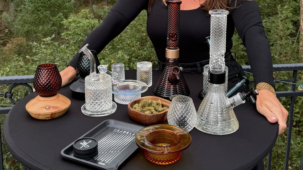 Woman sitting at a table with various smoking accessories outdoors.